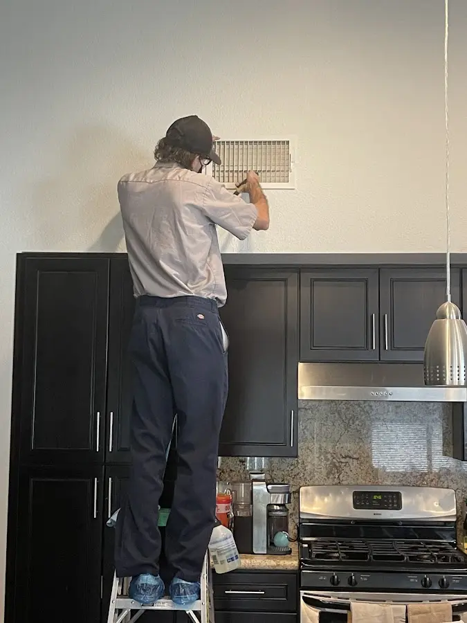 Technician inspecting an air vent during HVAC service in Aventura